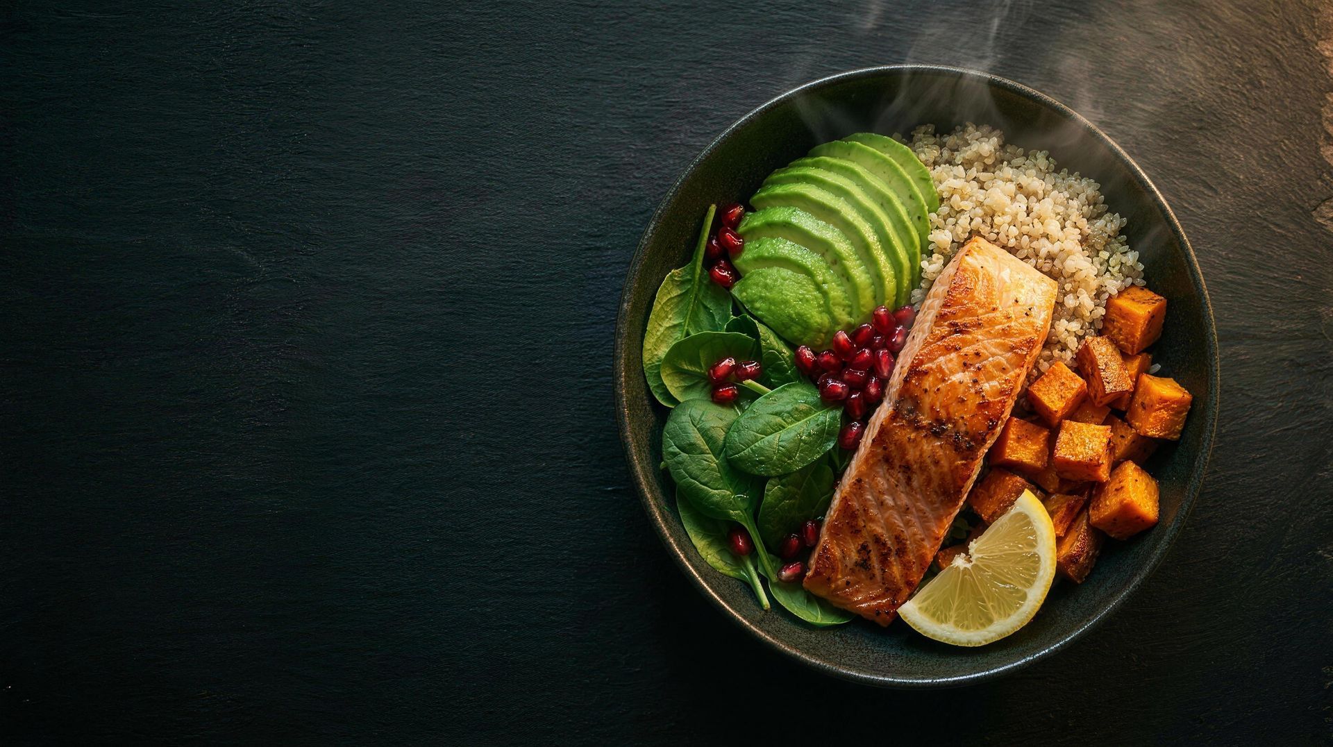 Gesunde Bowl mit Lachs, Avocado und Quinoa auf dunklem Schiefer